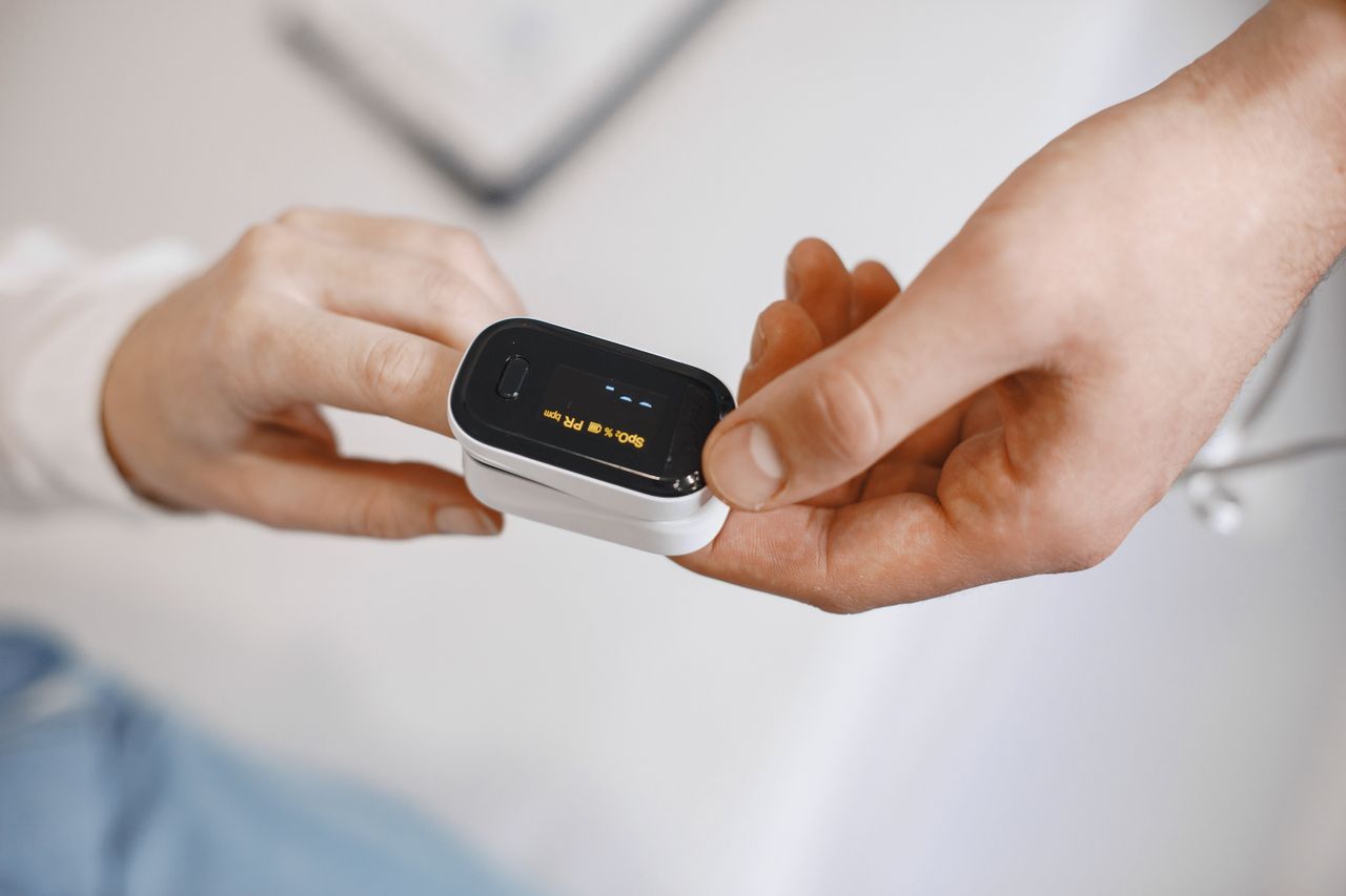 Close-up of a pulse oximeter on a finger, checking oxygen levels during a healthcare examination.